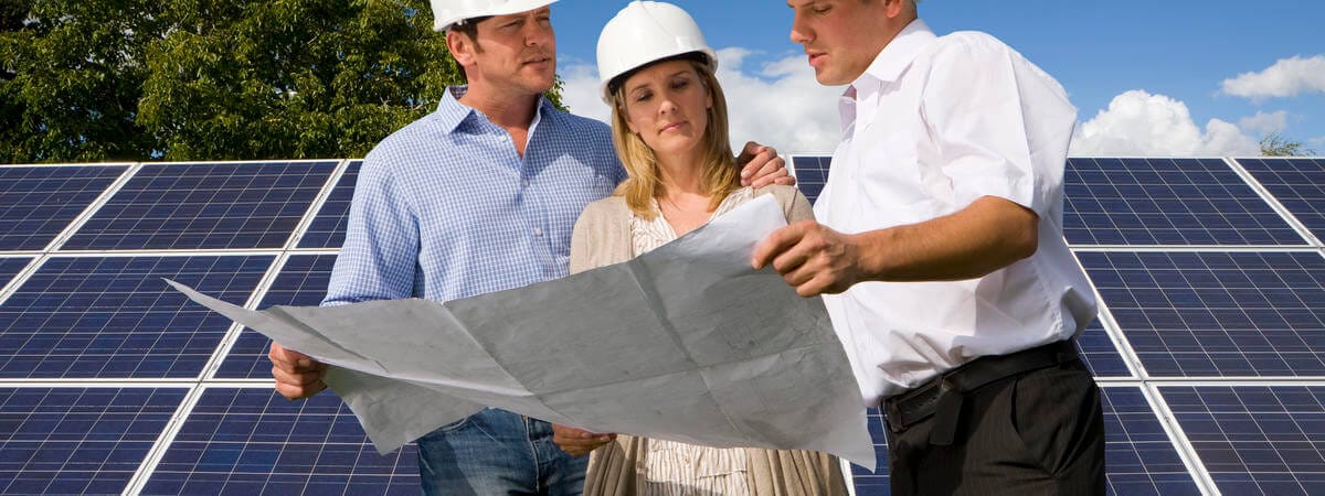 Three persons checking the schematics of solar panel installation