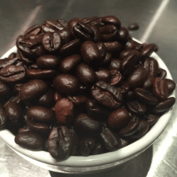 Dark roast coffee beans shown in a cup
