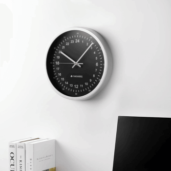 Navaris 24-hour analog clock on a wall above a desk