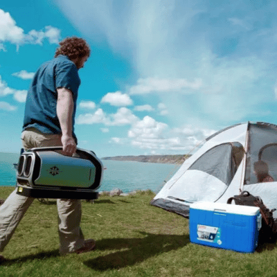 Man with a portable tent air conditioner approaching a tent