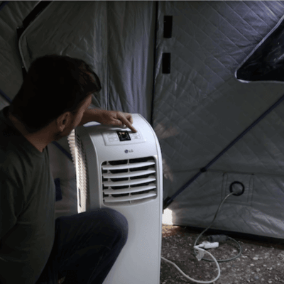 Man using a portable tent air conditioner inside his tent