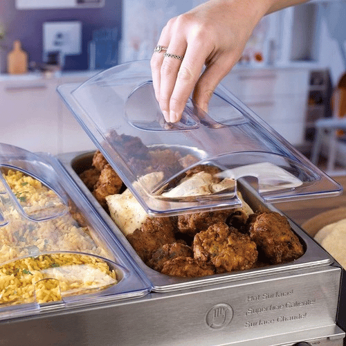 Hand lifting the lid off of a warming tray