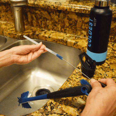 Person washing the straw of a stainless steel water bottle
