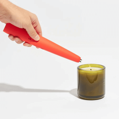 Person lighting a candle with a flameless lighter