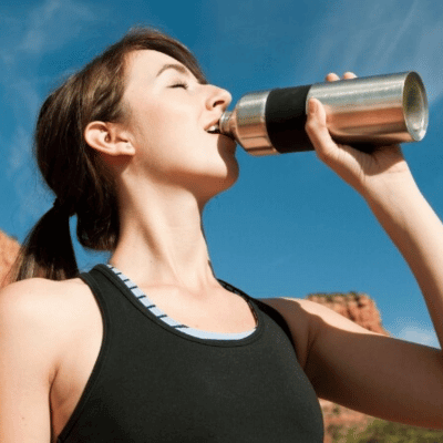 Woman hiker drinking water from a stainless steel water bottle