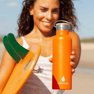 Woman at the beach showing her stainless steel water bottle