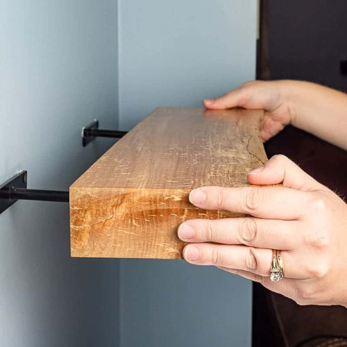 Person sliding a floating shelf on hidden brackets