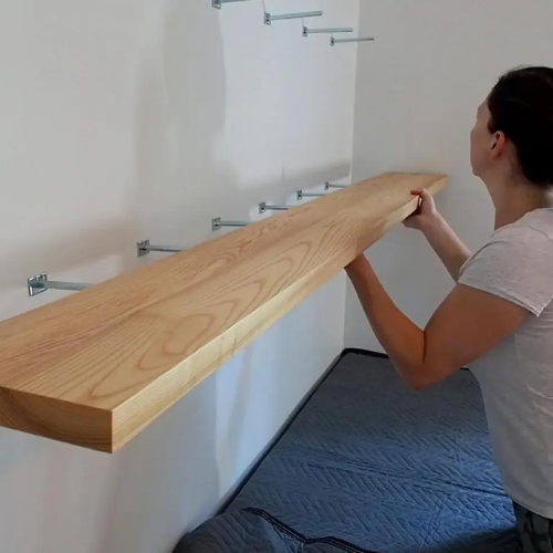 Person installing a floating shelf on a wall