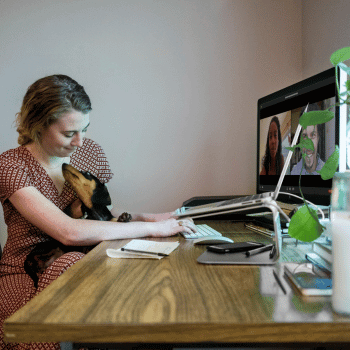 Woman working from home with her dog in her lap