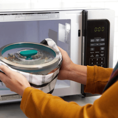 Stainless steel bowl being removed from a microwave oven