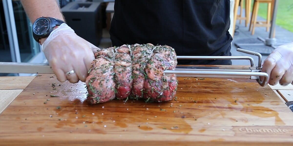 A person preparing meat for a spit roaster
