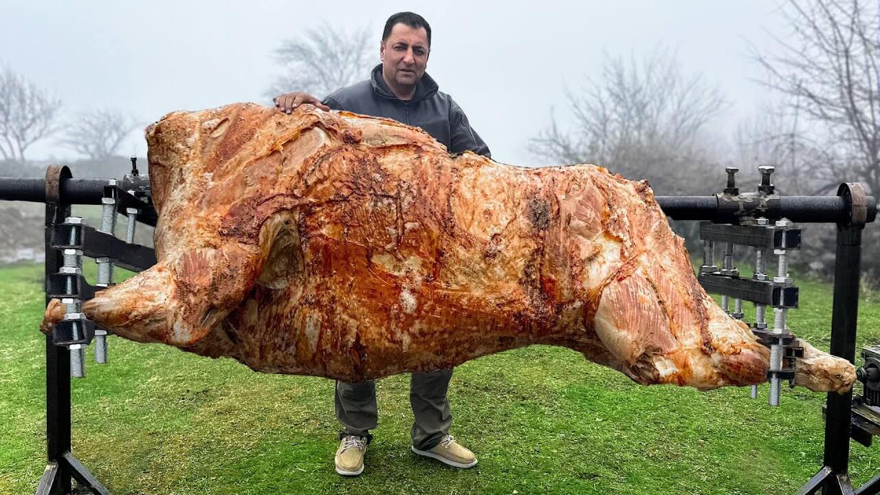 A man roasting a huge bull on a spit