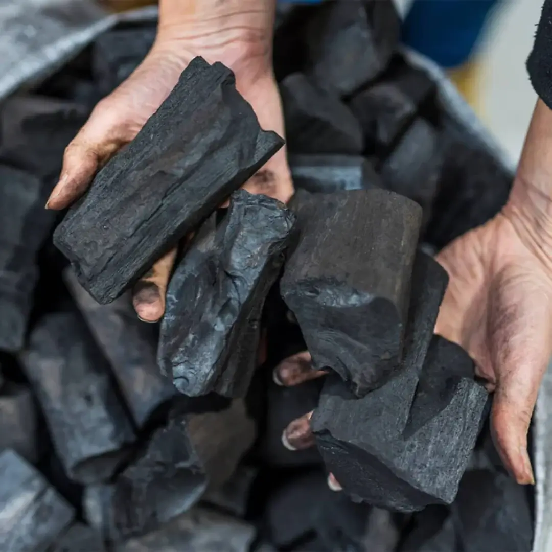 A person preparing charcoal for a spit roaster