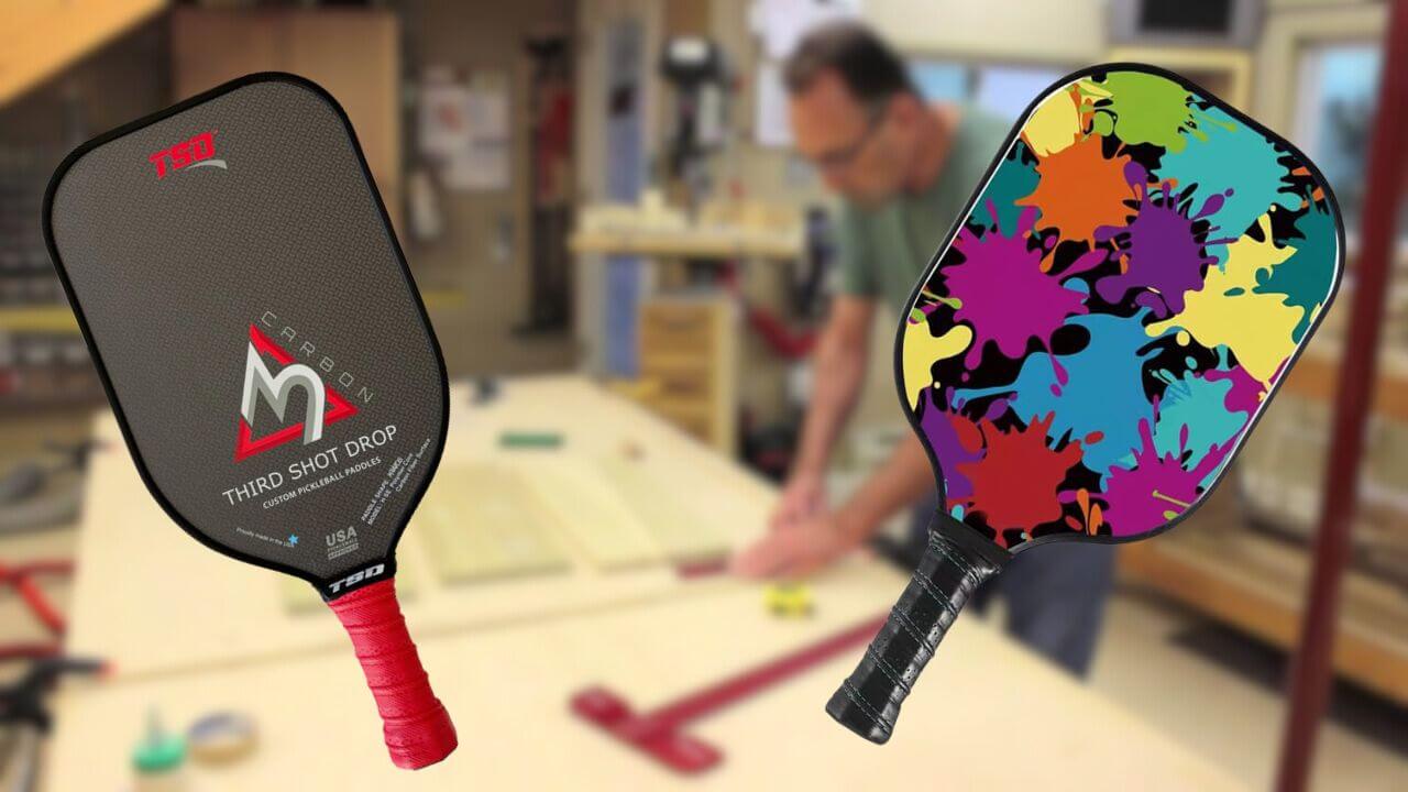 A carbon fiber pickleball paddle and a fiberglass pickleball paddle with paddle maker in the background