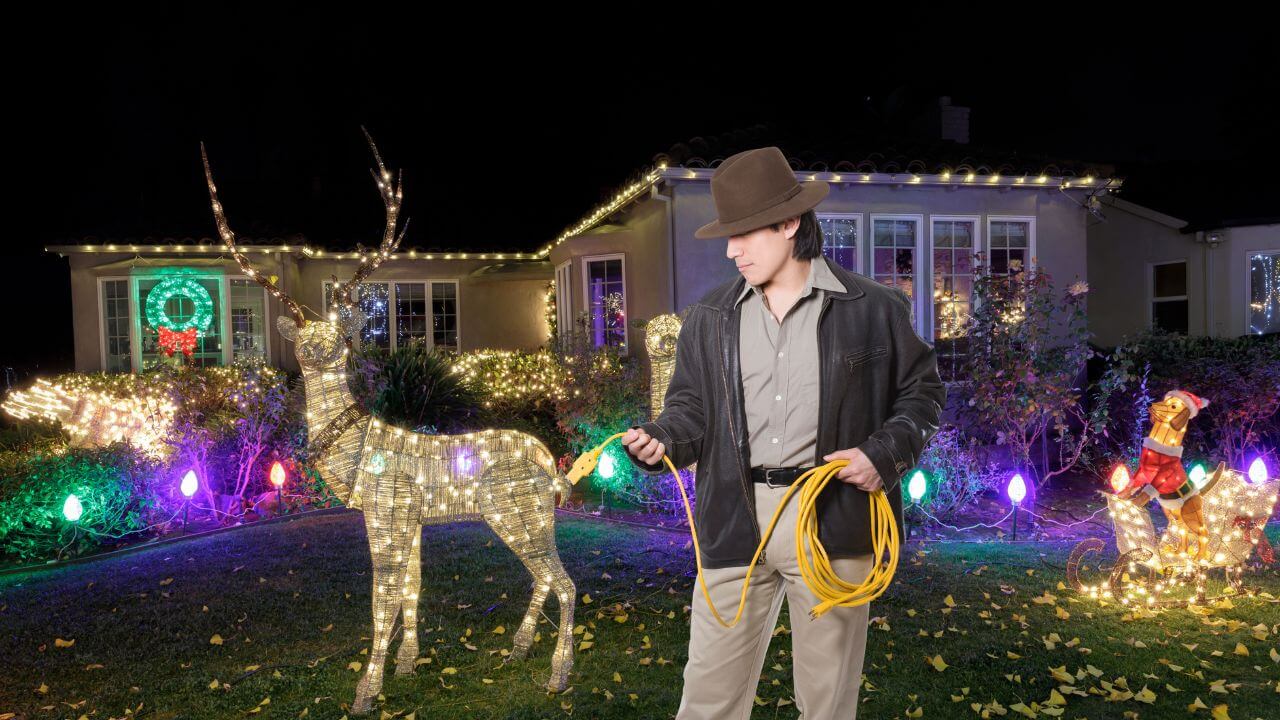 Man with an extension cord lighting up his outdoor Christmas decorations