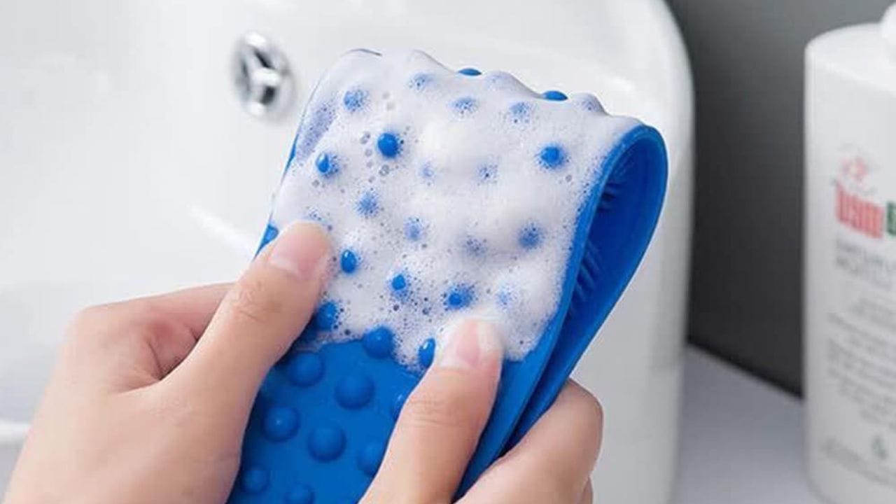 Person cleaning a silicone body scrubber