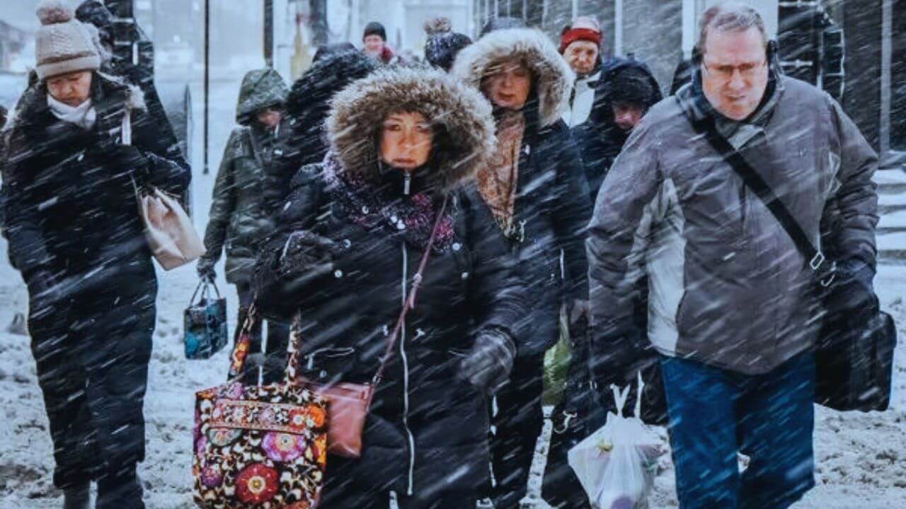 Group of people in winter weather wearing cold-weather gloves while walking on the sidewalk