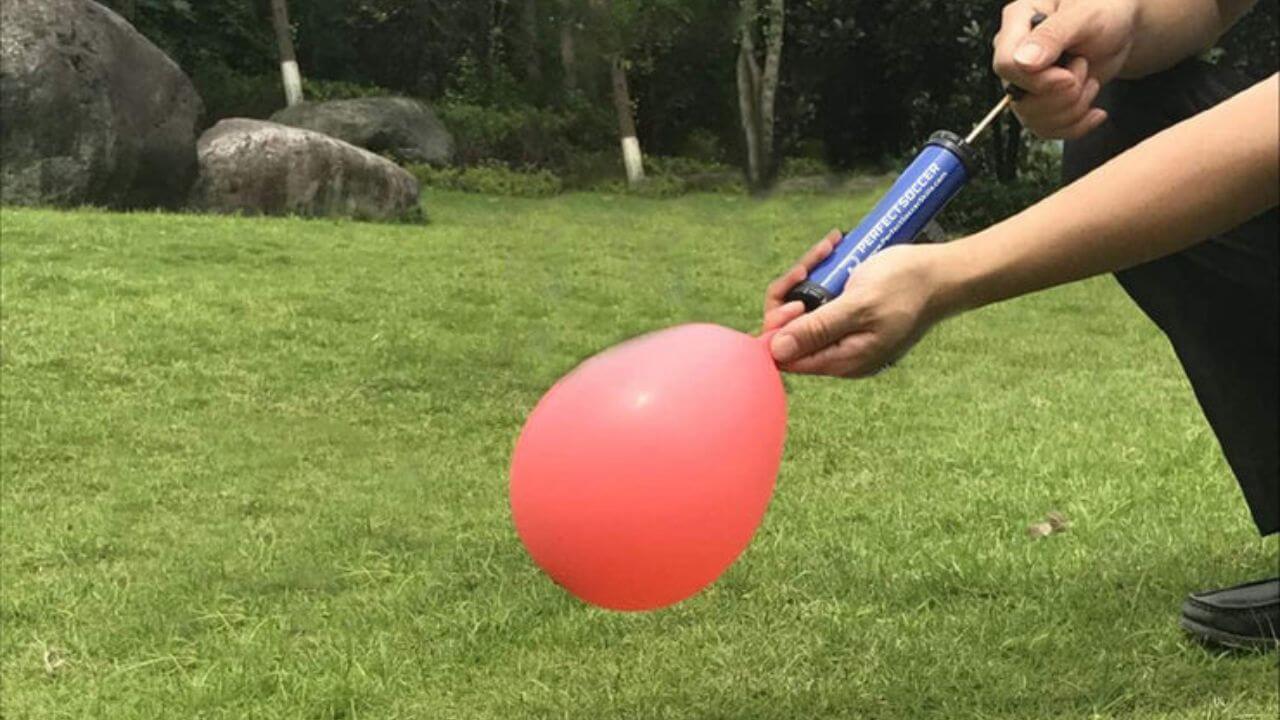 Person inflating a balloon with a ball pump