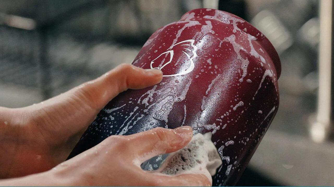 Person cleaning a stainless steel water bottle
