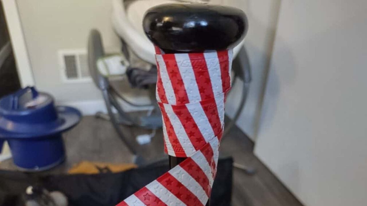Top of the handle of a wiffle ball bat showing the bat being wrapped with tape