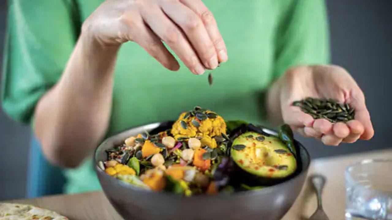 Person eating a salad with pumpkin seeds and other protein ingredients