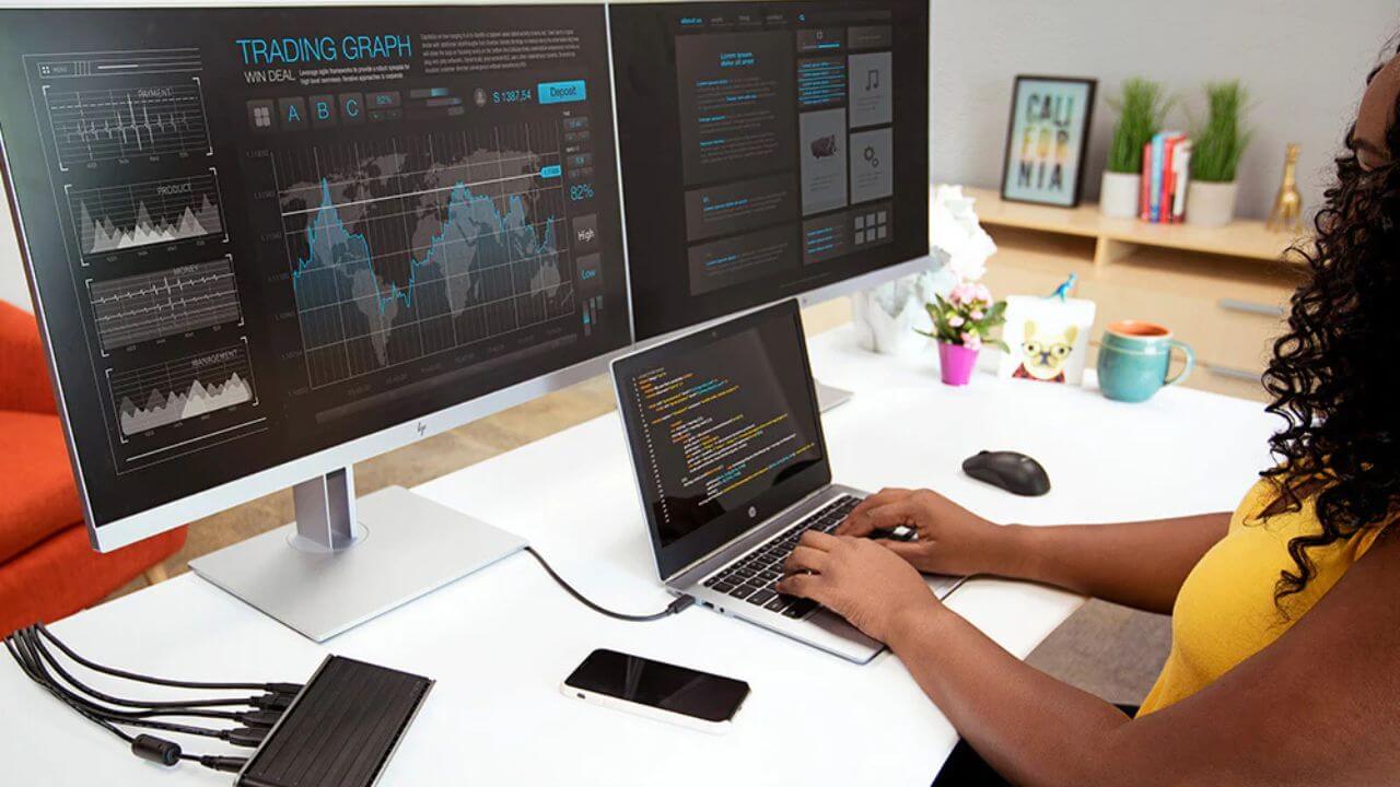 Woman with a laptop connected to two external monitors
