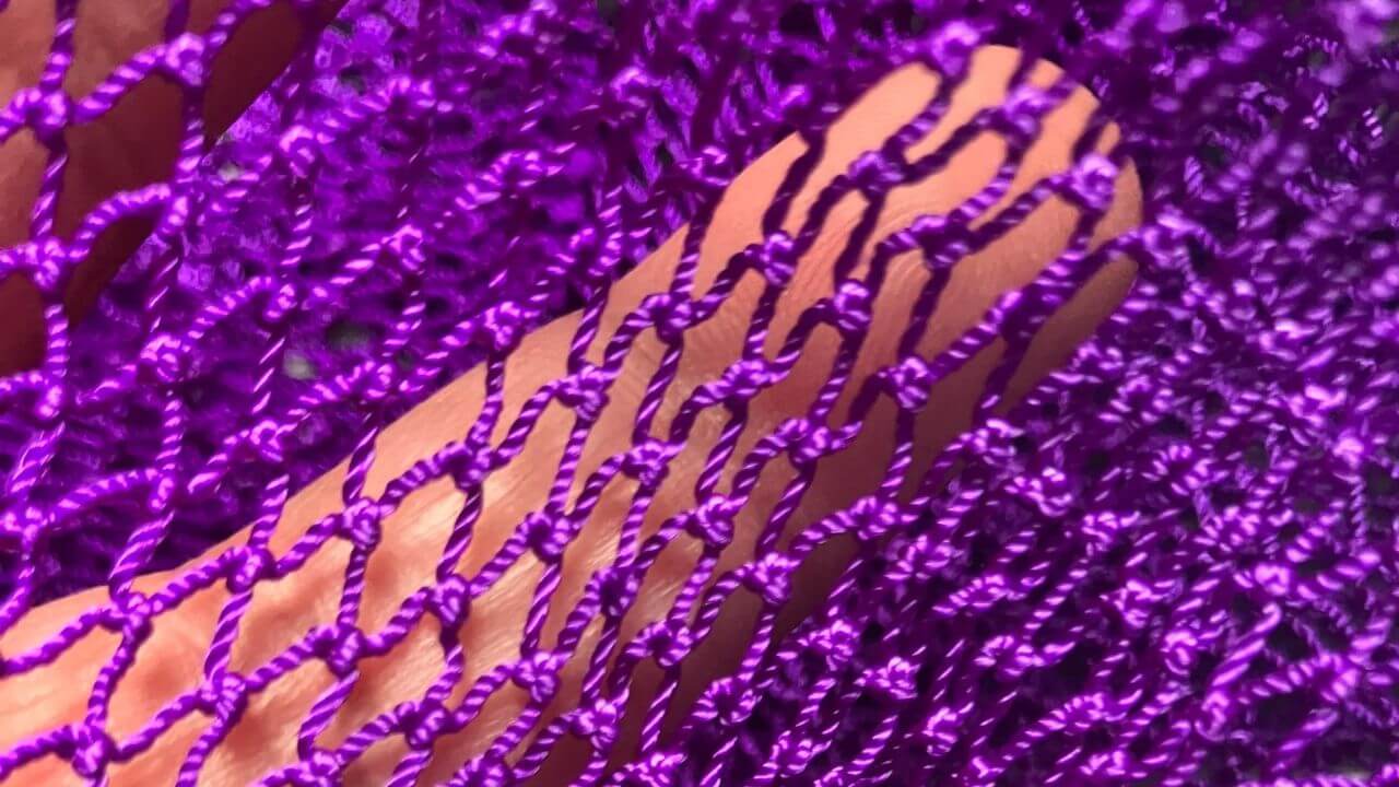 Finger showing an authentic African Net Sponge with clear defined woven knots