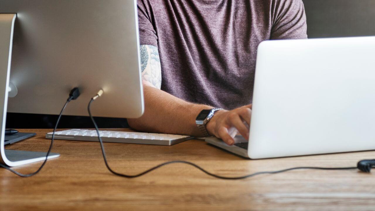 Man with a laptop connected to a wide monitor